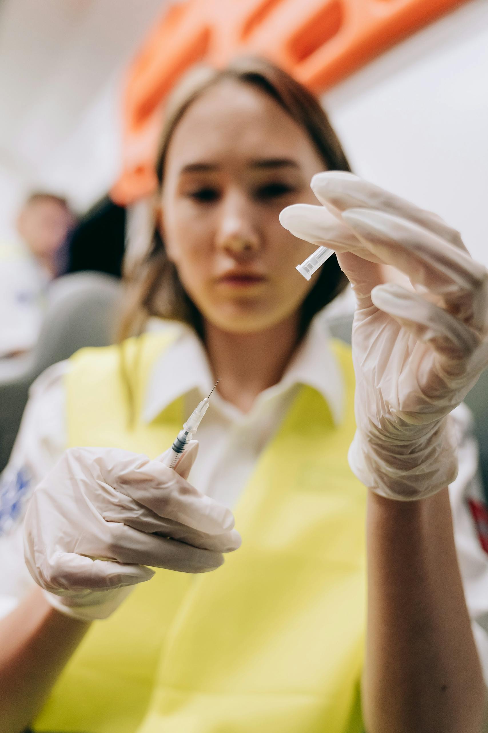 A focused female paramedic prepares a syringe inside an ambulance, showcasing emergency medical care.